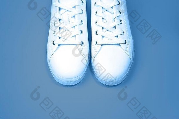 白色运动鞋位于蓝色背景上。蓝色铭文。顶视图。平铺。空间。