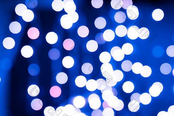 蓝色和粉色的圣诞树以黑色为背景，散焦闪烁的灯光，圣诞背景图案概念。
