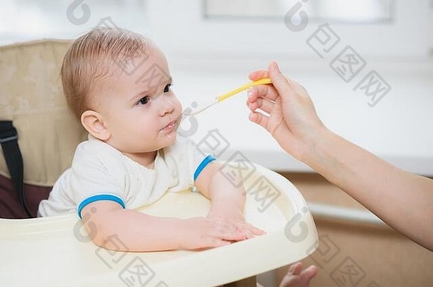 小孩子坐在椅子吃勺子
