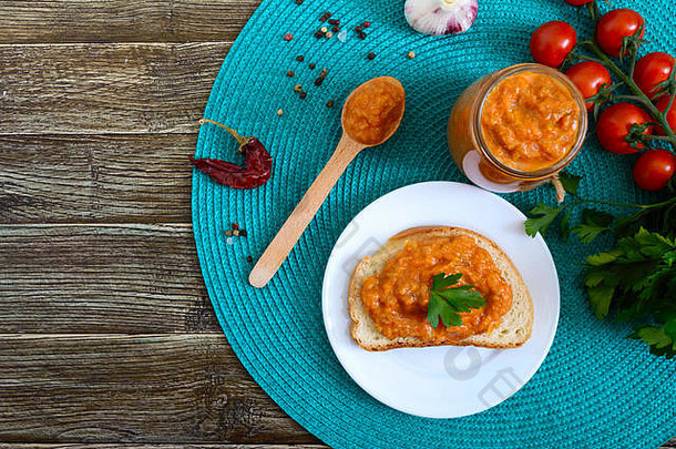 美味的南瓜鱼子酱放在罐子里，铺在桌上的白面包片上。鱼子酱配西葫芦、大蒜、胡萝卜、番茄酱。素食主义者