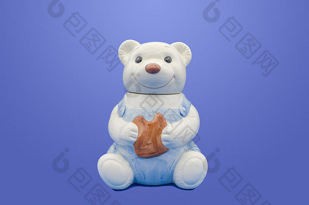 蓝色背景上孤立的泰迪熊形状的釉面陶器饼干罐