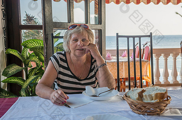 一位上了年纪的妇女正在度假村的咖啡馆里等晚餐。