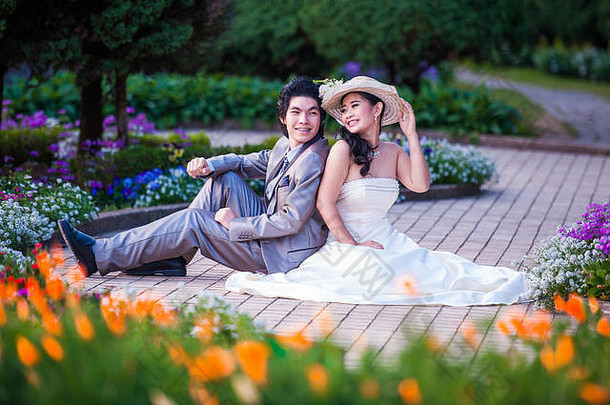 亚洲新娘和新郎一起坐在花园里