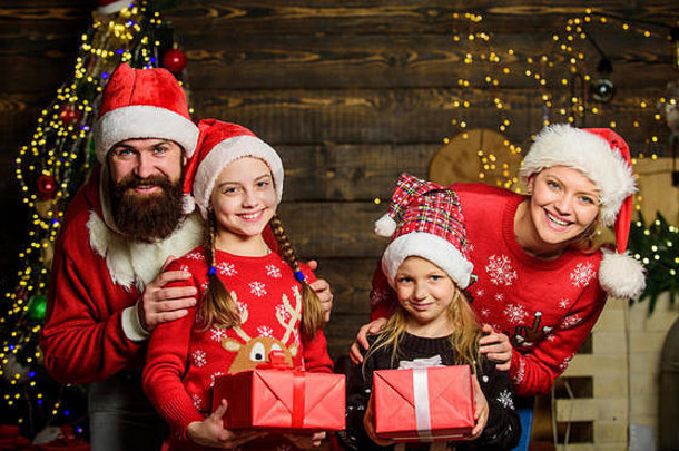 节礼日。节日快乐。父亲蓄着胡子，母亲和可爱的女儿们在圣诞树下。花时间和家人在一起。父母和孩子打开圣诞礼物。圣诞节的传统。