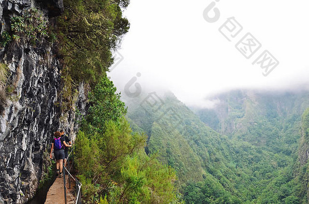 徒步旅行者走狭窄的路径边缘岩石被caldeirao海岸小道有雾的绿色山背景危险的徒步旅行葡萄牙语旅游吸引力雾多雾的
