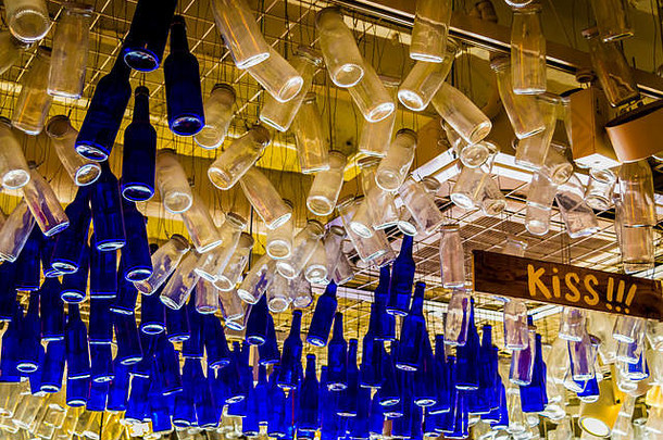 五颜六色的瓶子悬挂在天花板上，从下面。天花板采用蓝色透明玻璃瓶装饰。