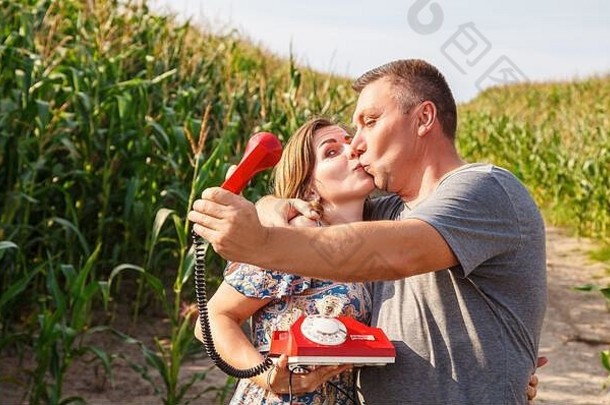 阳光明媚的夏日，一对接吻的情侣在玉米地里用复古手机进行自拍
