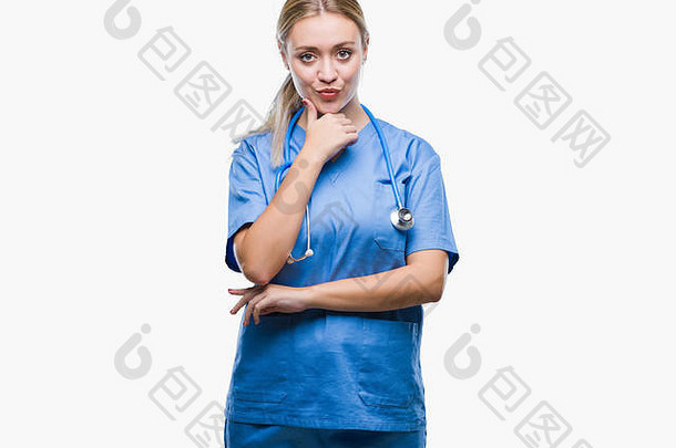 一位年轻的金发女外科医生，一位在隔离背景下的女医生，双臂交叉，手举在下巴上，自信地看着镜头。认为