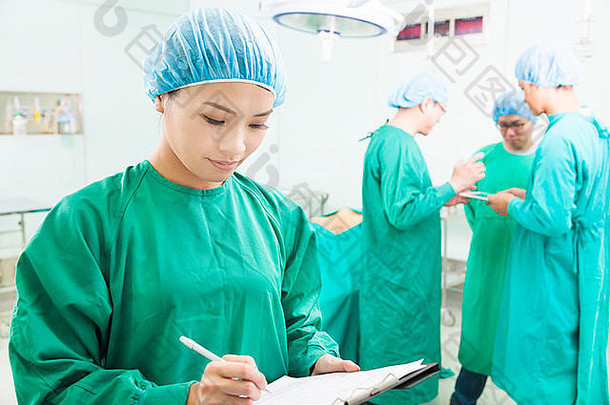 女人外科医生写作医疗记录团队操作房间