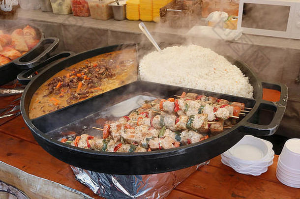街头快餐——在一个大的钢制煎锅上，煮米饭、辣椒酱牛肉和木串炒猪肉。春夏秋冬