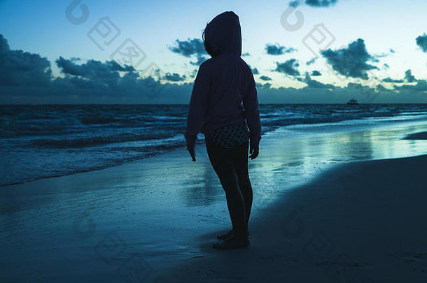 黑暗中一个小女孩站在海边的剪影照片