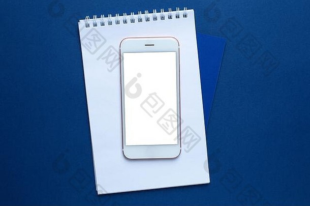 移动电话白色办公室笔记本经典蓝色的背景Copyspace前视图时尚的潘通色卡颜色