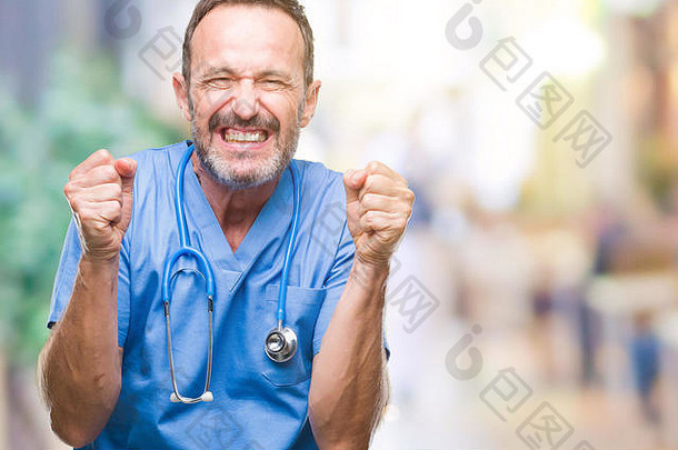 中年白发的高级医生，身穿医疗制服，在孤立的背景下，为成功而兴奋，举起双臂，微笑着庆祝胜利。