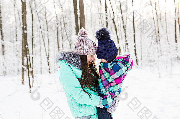 快乐家庭的母亲和孩子在森林里冬日散步