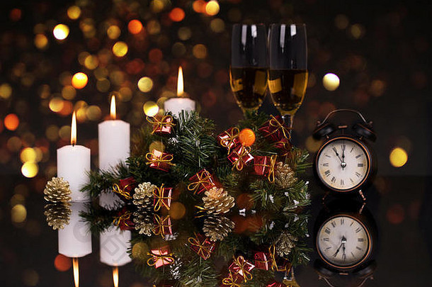 两个酒杯，配香槟、时钟、蜡烛和圣诞装饰品，黑色背景，反光。空间。圣诞快乐，新年快乐