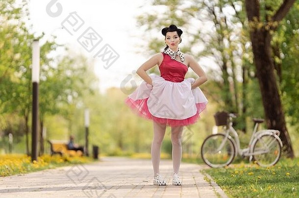 美丽的女孩粉红色的衣服发型风格舞蹈提出了公园阳光明媚的一天复古的风格照片