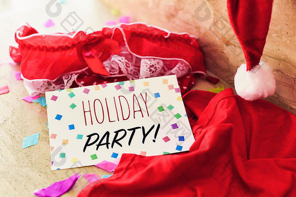 一条饰有白色花边的红色内裤，一条男士内裤，一顶圣诞老人帽，地板上还有一块写着“假日派对”的招牌
