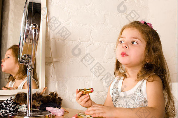 在镜子里涂口红的小可爱女孩，尝试化妆像成人，生活方式的人概念