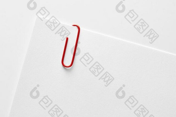 红色塑料回形针附在空白白纸的角上。特写镜头。