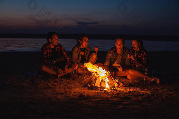 年轻的朋友们在海滩上用篝火野餐