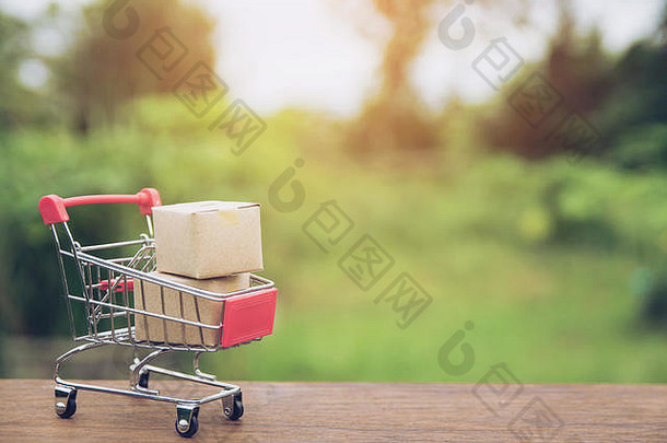 购物理念：在棕色木桌上的购物车中放置纸箱或纸盒。网上购物消费者可以在家购物，并提供送货服务。机智