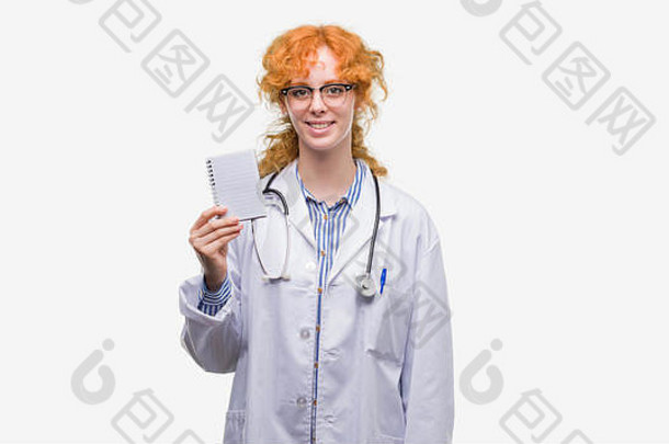 年轻的红色头发的人医生女人持有空白笔记本快乐脸站微笑自信微笑显示牙齿