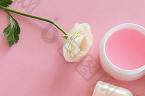 粉色背景上化妆品和精致花朵的俯视图。健康美容治疗。有机护肤品