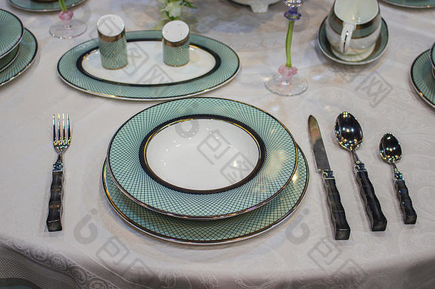 美丽的绿松石蓝色的白色盘子黄金桌布节日表格设置深平盘子刀叉勺子盐瓶胡椒