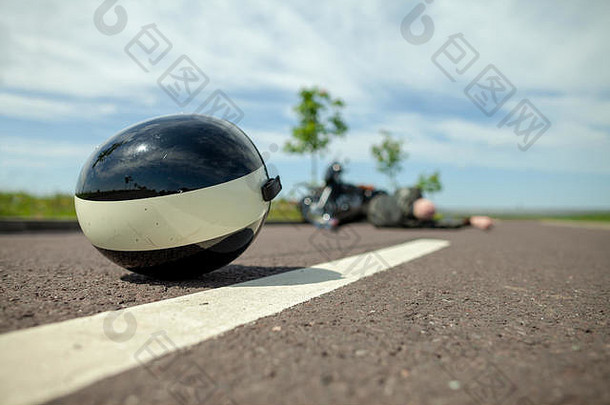 摩托车手头盔躺在摩托车事故附近的街道上