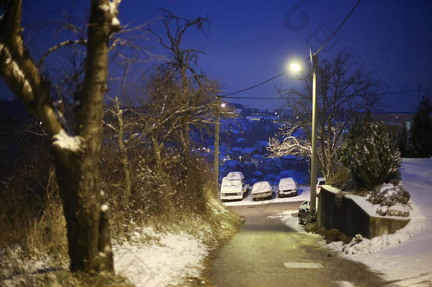日落时，村庄街道上停着的汽车被积雪覆盖。
