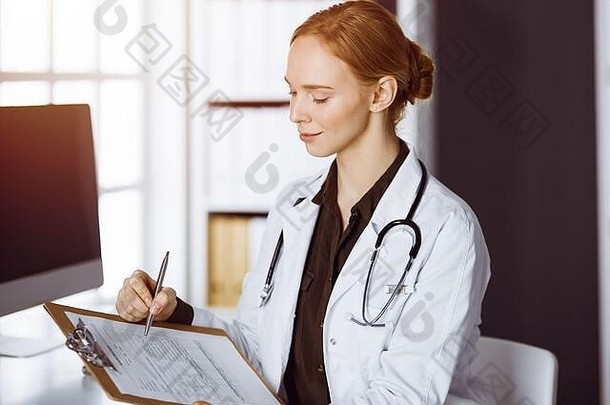 在诊所使用剪贴板的开朗微笑的女医生。工作场所友好的女医生肖像。医学概念