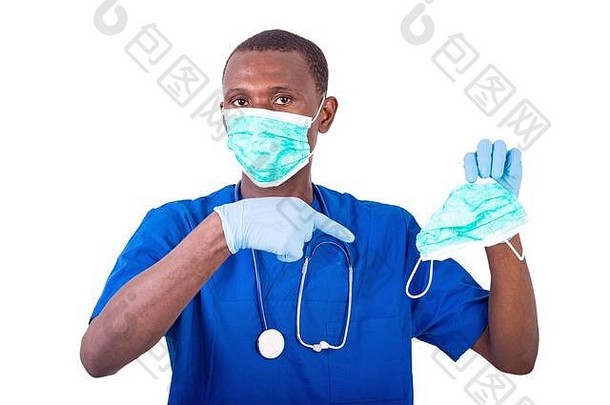 年轻的医生穿着制服，手持听诊器，用手指指着医用口罩。