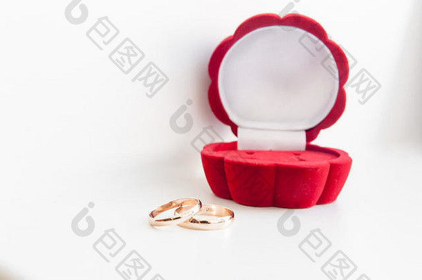 婚礼两枚红色盒子中的金戒指，在白色背景上用空间隔开