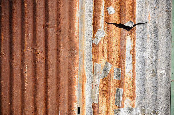 旧城里生锈的锌波纹金属墙。