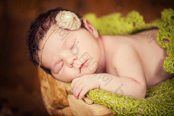 一个刚刚出生的孩子躺在树桩上，戴着圆锥形和浆果的花环睡觉。