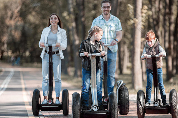 一家人和两个孩子在公园里玩电动迷你气垫船。