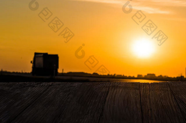 空的乡村木桌面，运动模糊的<strong>卡车</strong>在日落的<strong>背景</strong>下。可以蒙太奇或显示您的产品。