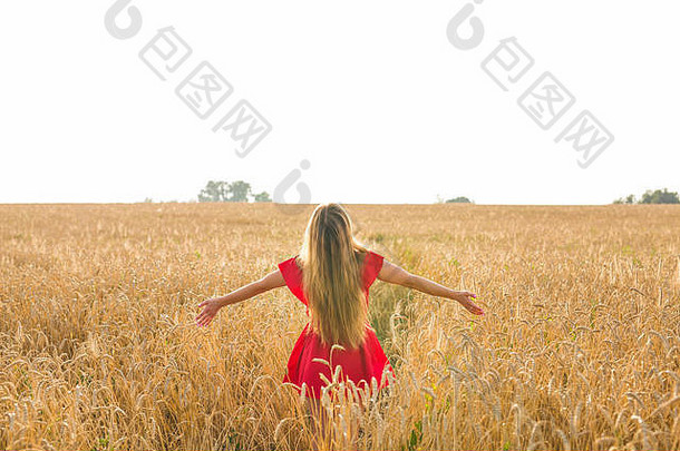 年轻女子张开双臂，在阳光明媚的夏秋时节尽情享受着后景色
