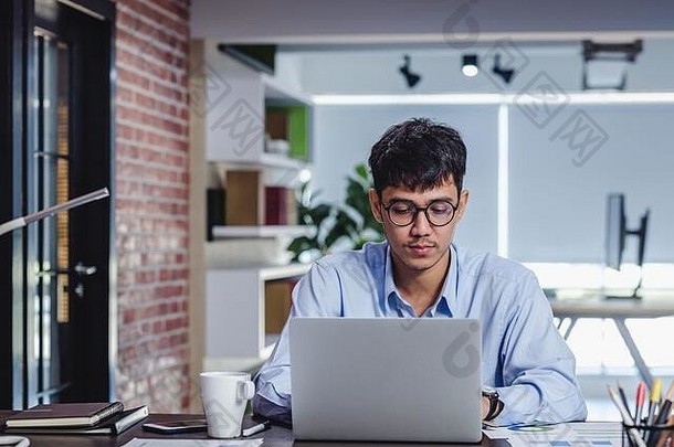 亚洲商人在办公室的办公桌上用笔记本电脑和文件工作。数字工作流在线商务生活方式概念
