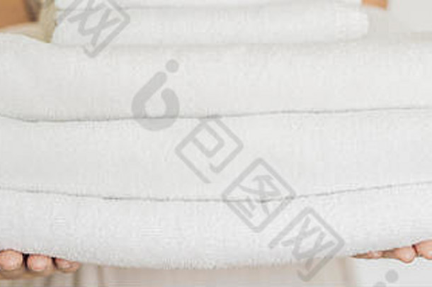 一个女人拿着一堆白色毛巾。酒店、洗衣房、水疗横幅、长格式的服务理念