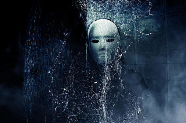 神秘的黑衣女人戴着白色面具藏在蜘蛛网后面，书的封面背景很恐怖