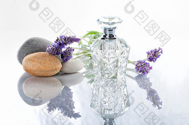 一瓶薰衣草香水，旁边放着一些白色的石头。
