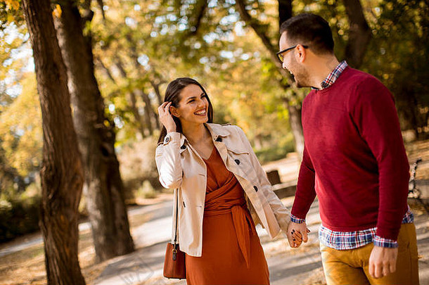 可爱的年轻夫妇在秋天公园散步
