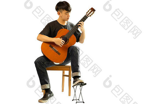 在白色背景下弹奏古典吉他的亚洲男子。