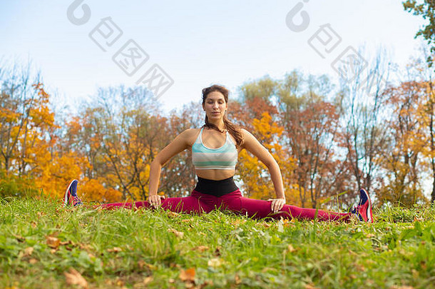 苗条的运动型女子在秋季城市公园伸展身体