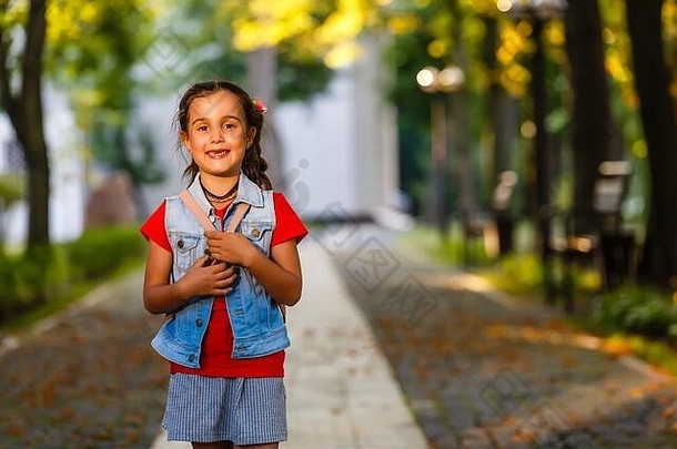 早晨，在温暖的阳光下，小女孩背着背包走进学校。教育理念。
