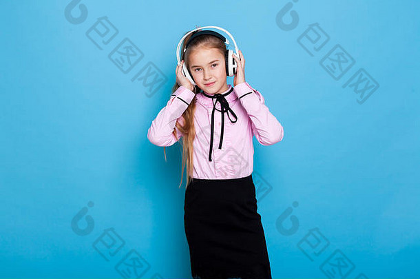 一个戴着耳机在蓝色背景上听音乐的美丽女孩的肖像