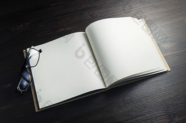 黑色木质背景上空白宣传册和眼镜的照片。为文本空间。