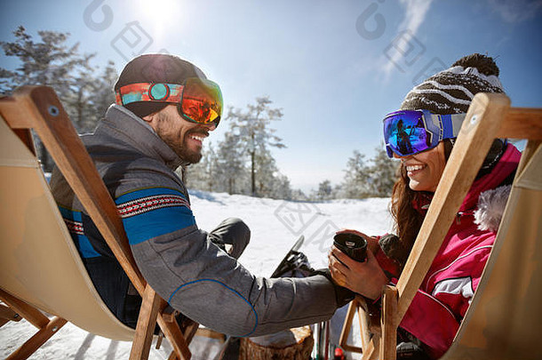 戴着滑雪镜躺在日光浴床上喝茶的情侣