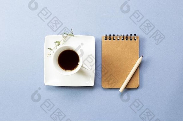 蓝色背景上的笔记本和黑咖啡。平面布局、俯视图、空间。工作和学习场所